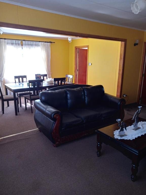 uma sala de estar com um sofá de couro preto e uma mesa em HOWENH em Porvenir
