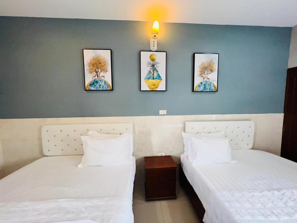 two beds in a room with three pictures on the wall at Hoang Ngan 1 Hotel - TP. Vinh in Vinh