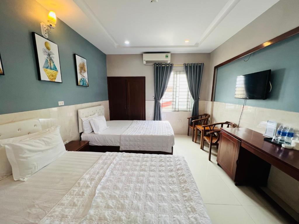 a hotel room with two beds and a television at Hoang Ngan 1 Hotel - TP. Vinh in Vinh