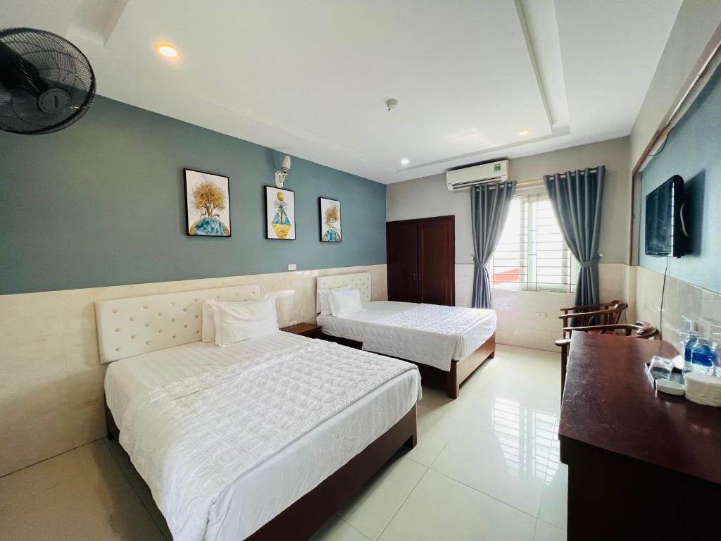 a hotel room with two beds and a desk at Hoang Ngan 1 Hotel - TP. Vinh in Vinh