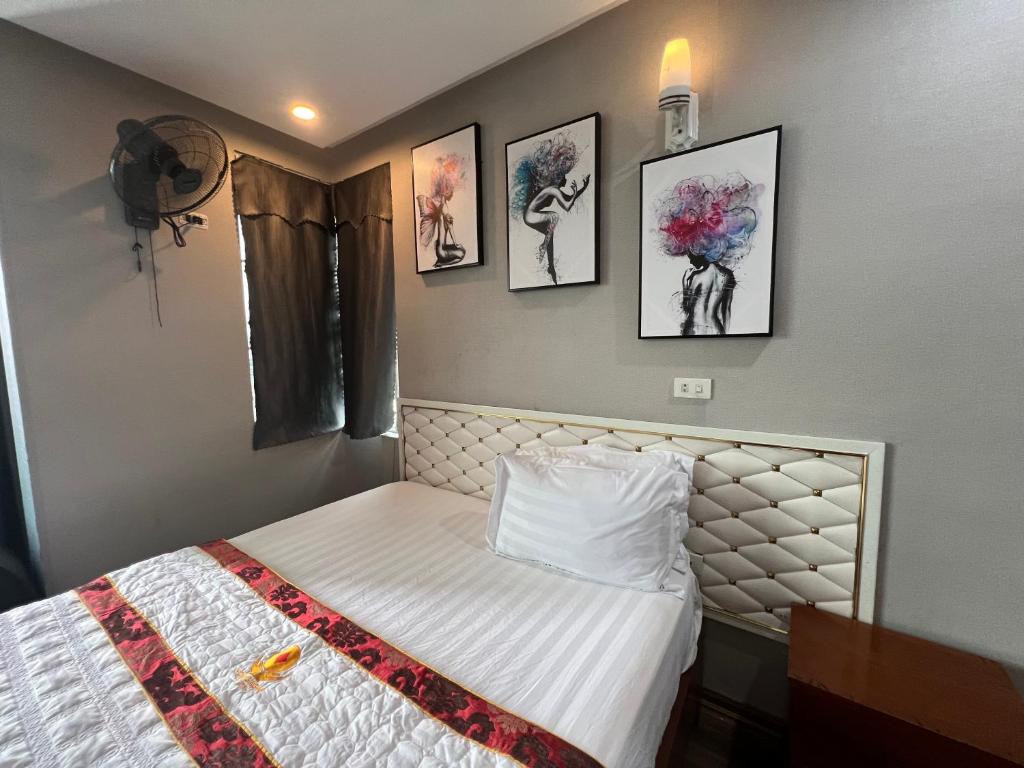 a bedroom with a bed and four pictures on the wall at Hoang Ngan 1 Hotel - TP. Vinh in Vinh