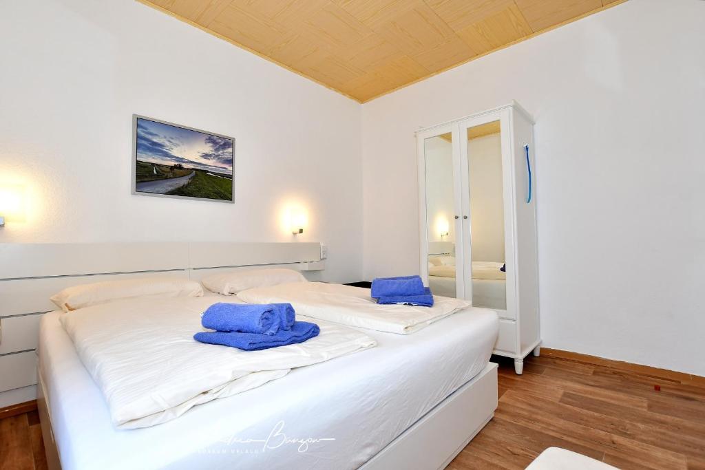 ボルクムにあるHaus-Herrmann-2のベッドルーム1室(白いベッド1台、青いタオル付)