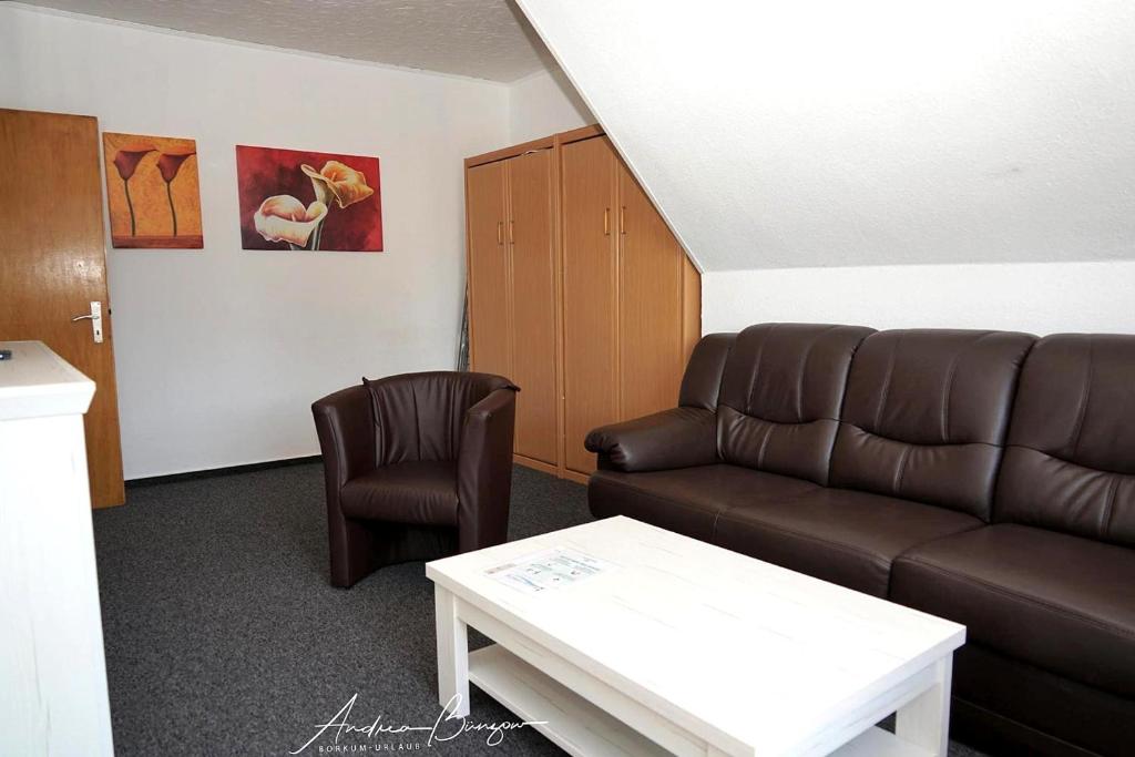 Haus-Koenigsduene-I-4 في بوركوم: غرفة معيشة مع أريكة وكرسي