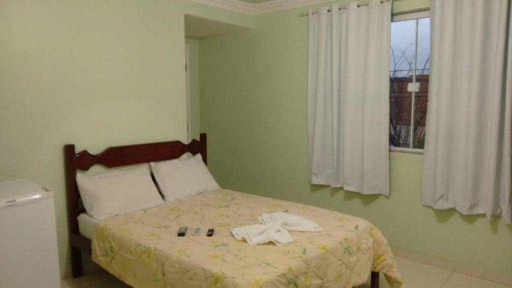 a bedroom with a bed with a robe on it at Pousada Sol da Justiça in Campos dos Goytacazes