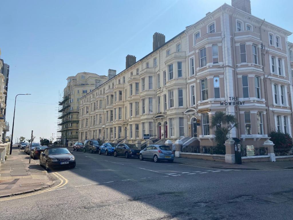 un gran edificio con coches aparcados en el lateral de la calle en The Mowbray, en Eastbourne