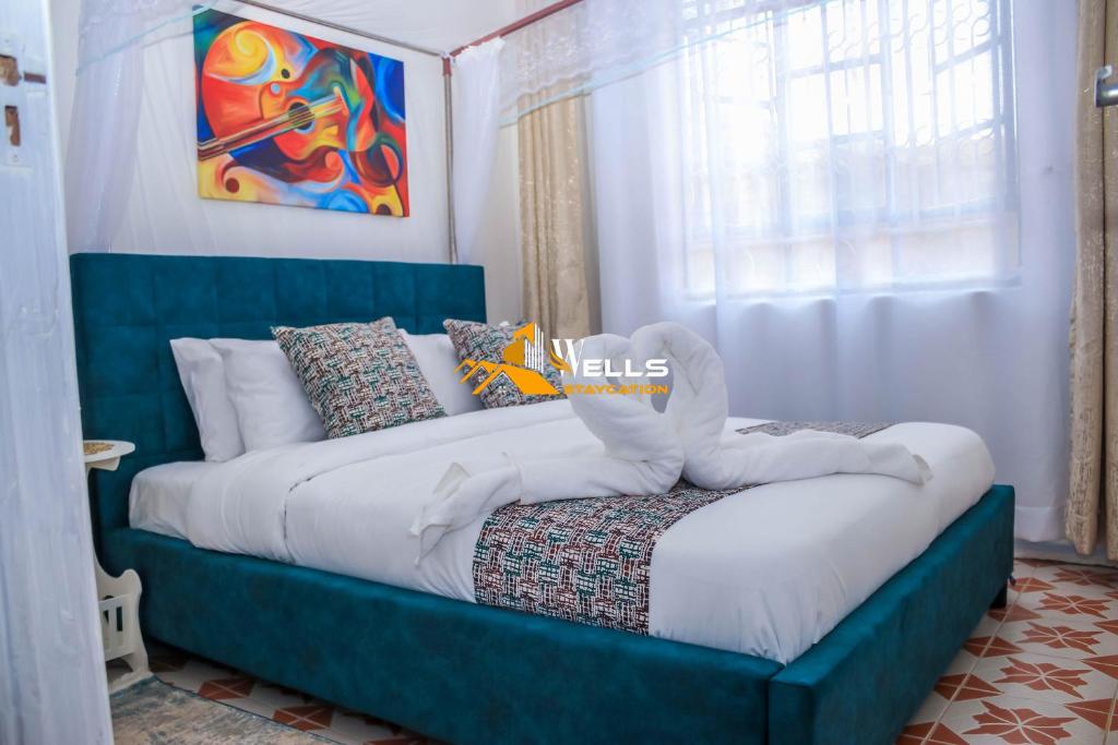 una camera da letto con letto blu, lenzuola e cuscini bianchi di Wellstaycation a Bungoma