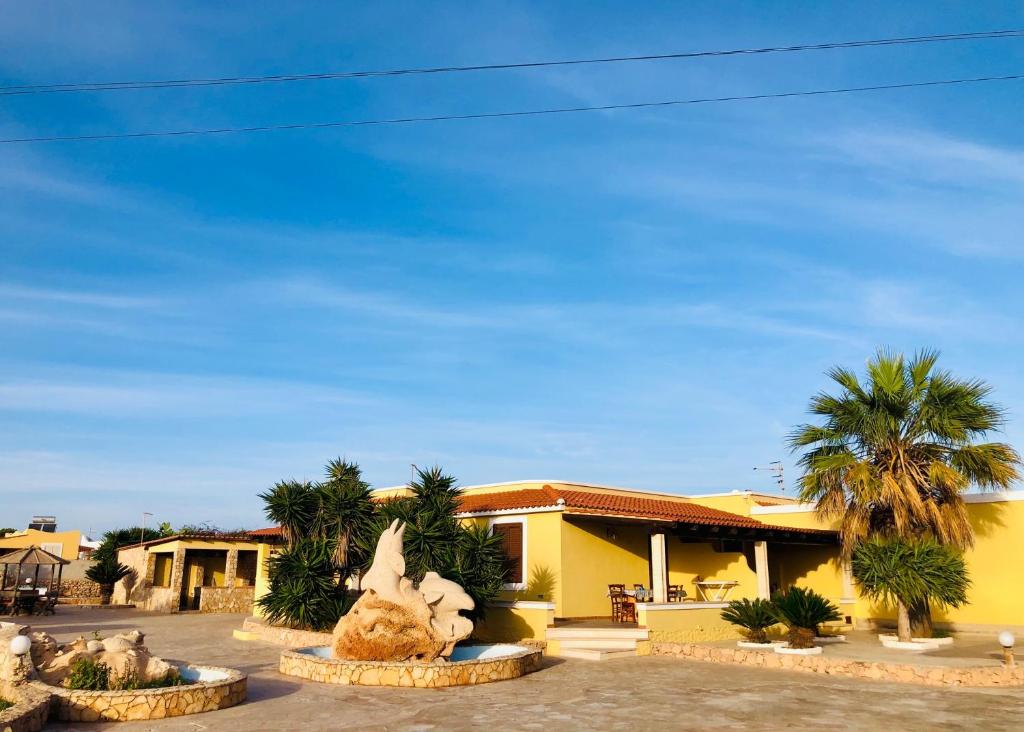 a yellow house with a statue in front of it at Residence Il Melograno in Lampedusa