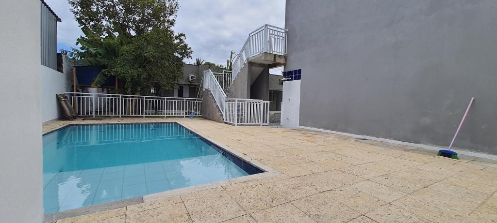 a swimming pool sitting next to a white building at Pousada Village Maitinga in Bertioga