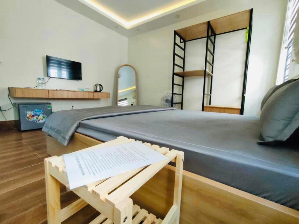 a bedroom with a large bed with a chair and a table at Hương Cảng Homestay in Hai Phong