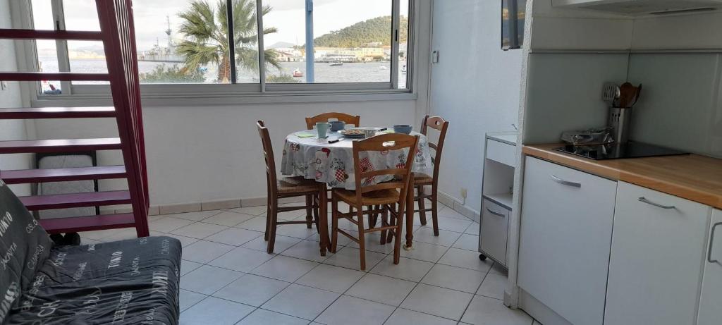 eine Küche mit einem Tisch und Stühlen sowie einem Tisch und einem Fenster in der Unterkunft Bright duplex with magnificent sea view in Saint-Mandrier-sur-Mer