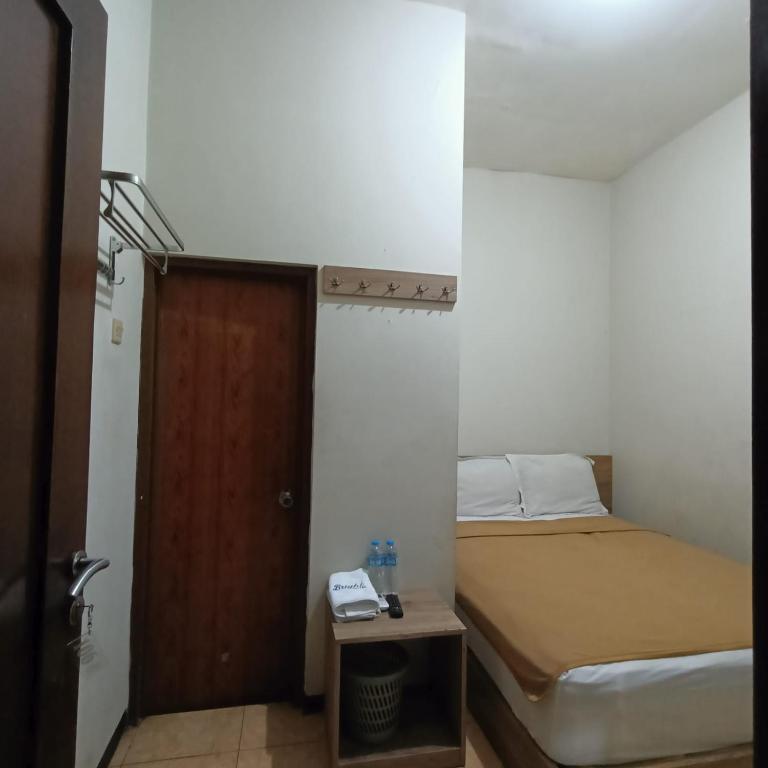 um pequeno quarto com uma cama e uma porta em Fans Bright Batavia em Jakarta