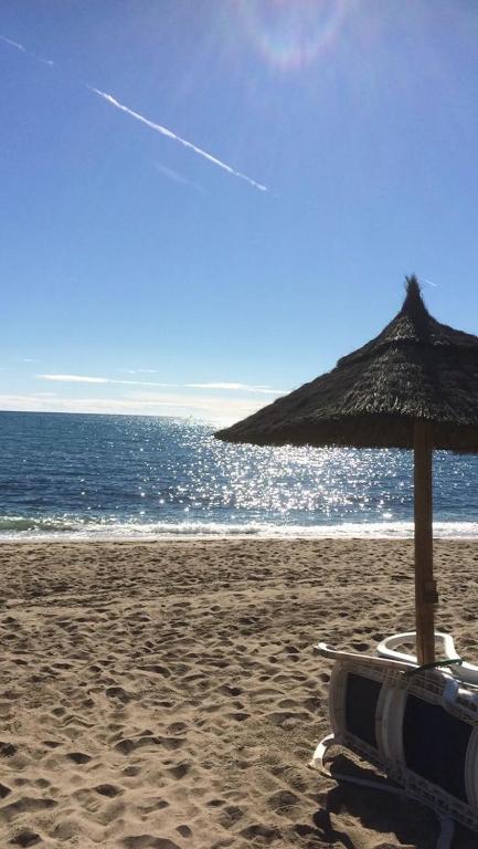 a beach chair with an umbrella on the beach at Beach apartment LA CALA DE MIJAS in La Cala de Mijas