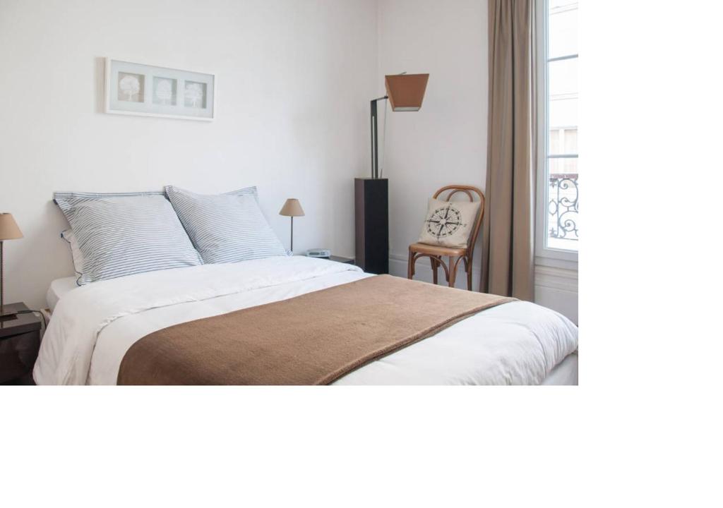 1 dormitorio con 1 cama, 1 silla y 1 ventana en La petite maison parisienne en Levallois-Perret