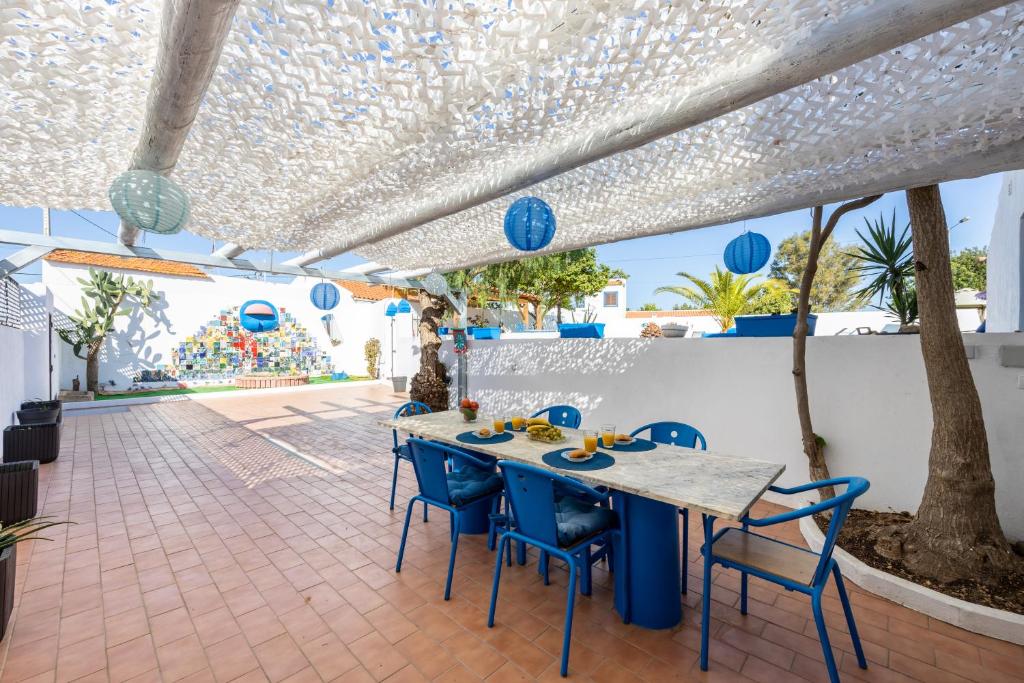 een patio met een tafel en blauwe stoelen bij Porta 27 in Silves