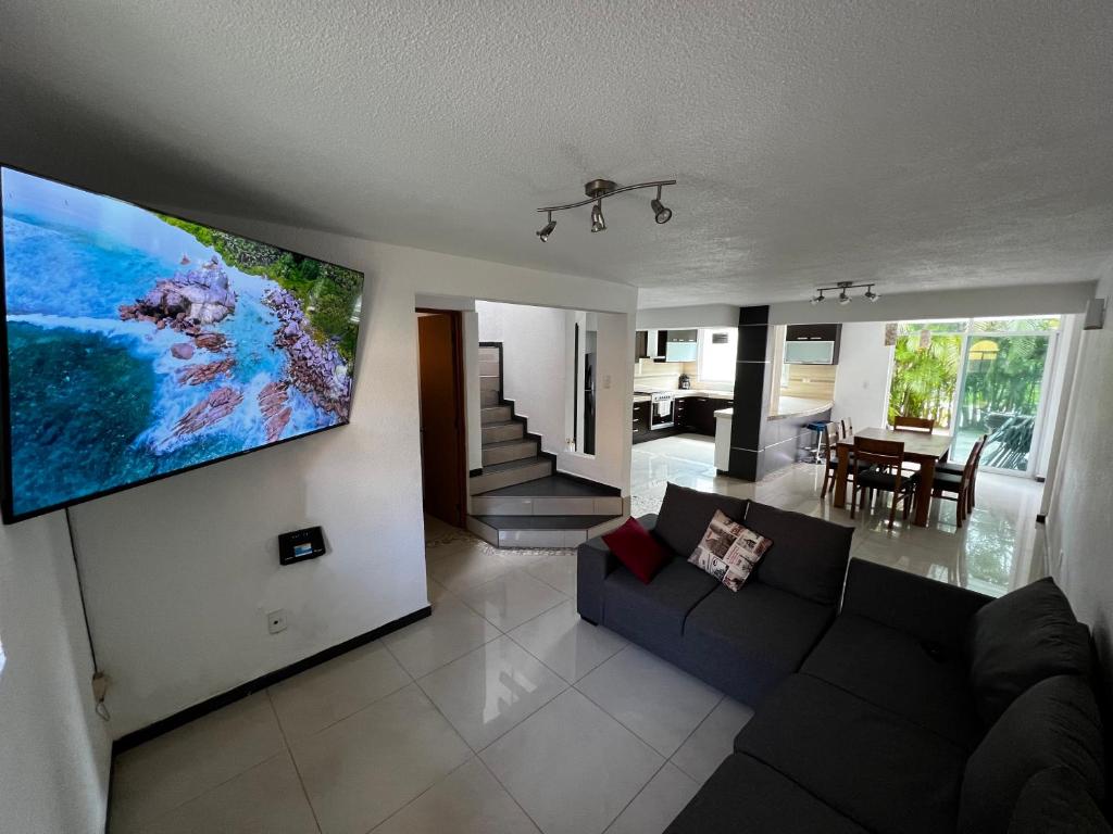 een woonkamer met een bank en een tv aan de muur bij Casa Lían in Cuernavaca