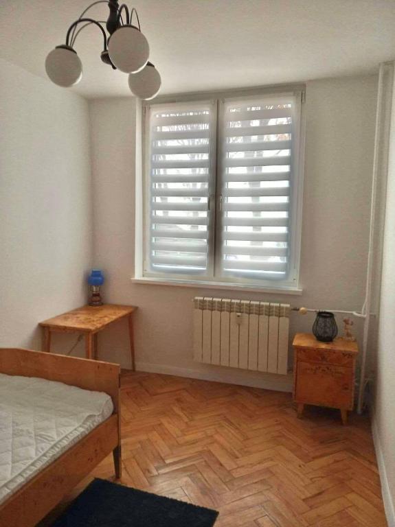 a bedroom with a bed and a window with blinds at Apartament Doris in Ciechocinek