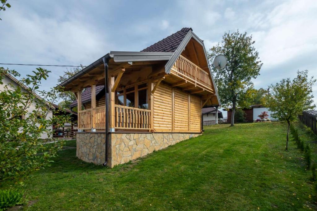 a log cabin with a deck on a lawn at Brvnara Oganj in Čajetina