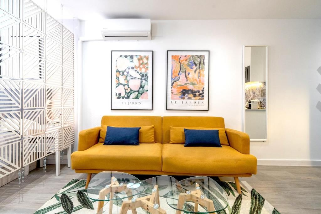 馬貝拉的住宿－XPCE MARINO 2 MARBELLA，客厅配有黄色沙发和绘画作品