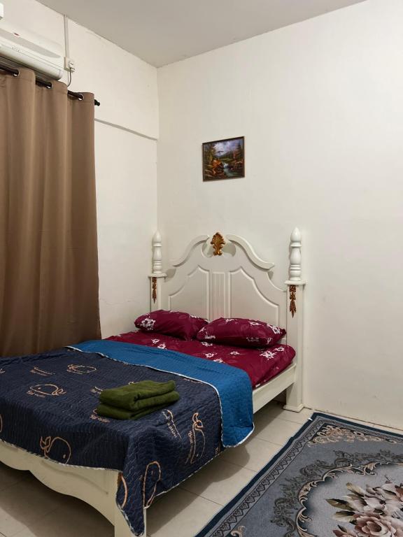 a bedroom with a bed with red and blue sheets at Azlina Homestay Jerantut in Jerantut