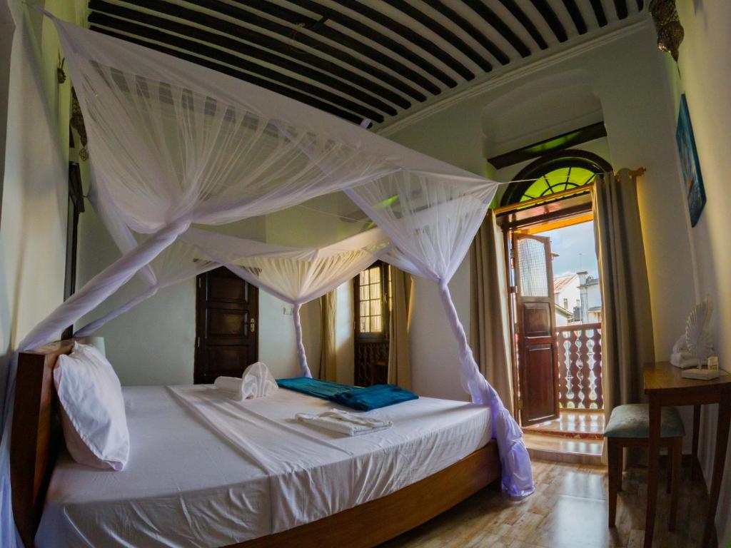 a bedroom with a white bed with a canopy at Aurelia Zanzibar in Ngambo