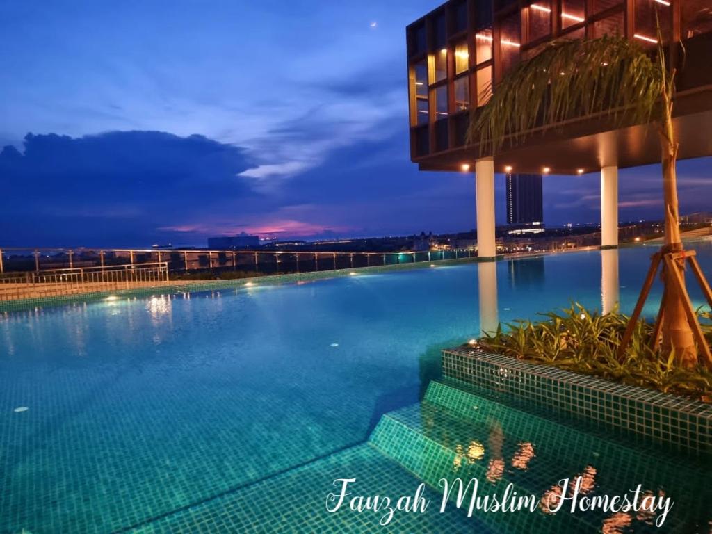 a swimming pool in front of a building at night at Bali Residences by Fauzah Muslim Homestay in Melaka