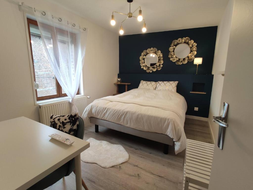 Schlafzimmer mit einem Bett, einem Tisch und einem Spiegel in der Unterkunft Résidence Beaudelot in Saint-Saulve