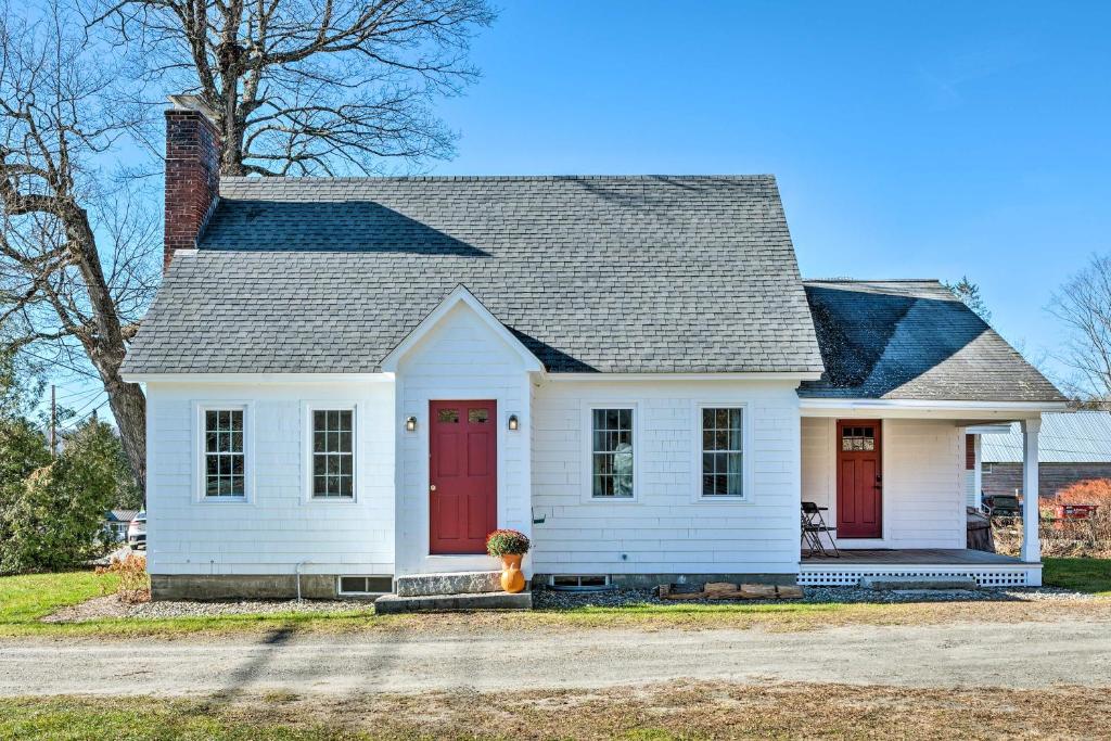 uma casa branca com portas vermelhas em Charming Farmhouse Walk to Village and Trails! em East Burke