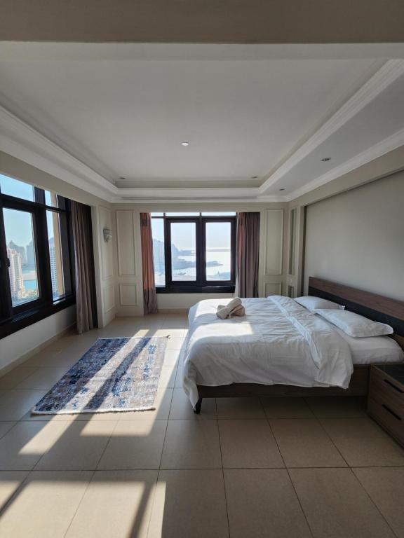 a bedroom with a large bed and large windows at Luxurious 2-bedroom Apartment with Sea View in Doha