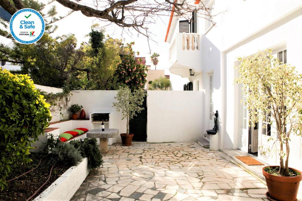 une cour d'une maison blanche avec une passerelle en pierre dans l'établissement Cushy Apartment with garden in Estoril, à Estoril
