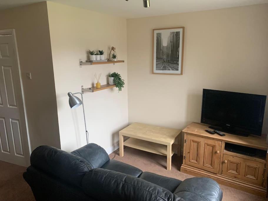 a living room with a couch and a flat screen tv at 1 bedroom townhouse in North Yorkshire in Harrogate