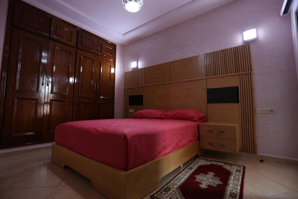 1 dormitorio con 1 cama grande con colcha roja en APPARTEMENT AMIRA iFRANE, en Ifrane