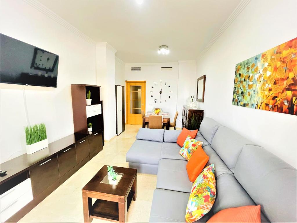 ein Wohnzimmer mit einem Sofa und einem TV in der Unterkunft ARENAL GOLF HOME in Benalmádena