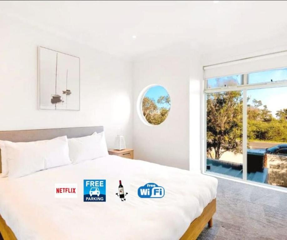a white bedroom with a bed and a window at 2Bdrm Beachside Town House with Ocean Views in Seaford