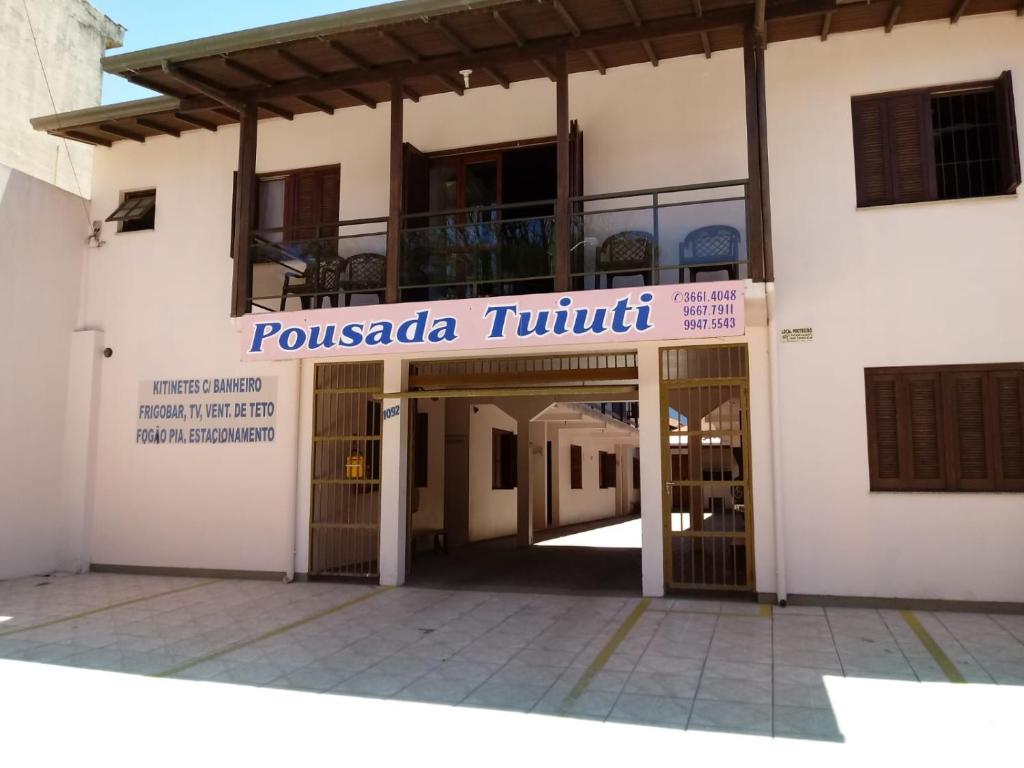a building with a sign that reads pussada truth at Pousada Tuiuti in Tramandaí