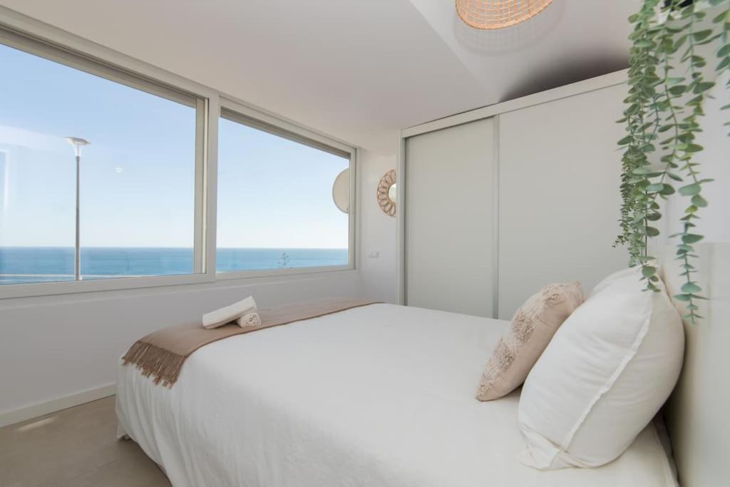 Schlafzimmer mit einem weißen Bett und großen Fenstern in der Unterkunft Casa A-Mar in Sesimbra