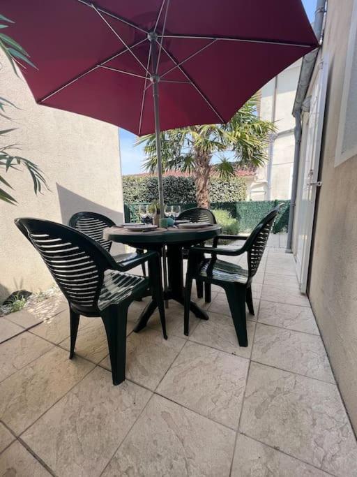 une table avec des chaises et un parasol sur une terrasse dans l'établissement Appartement et cour St Jean de Monts +parking, à Saint-Jean-de-Monts
