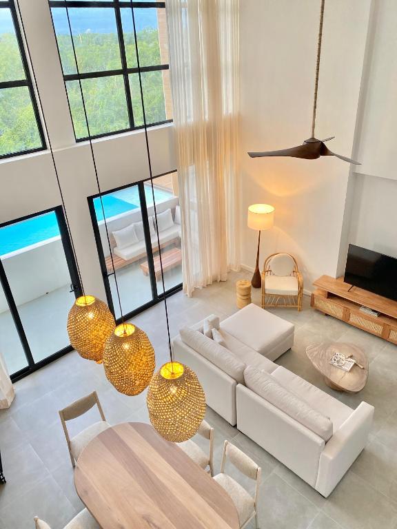 a living room with white furniture and large windows at Lumina at Flats Punta Cana Village in Punta Cana