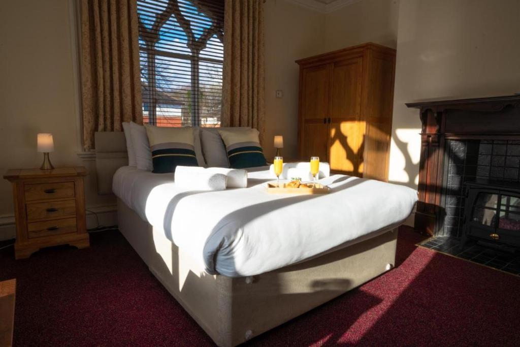 a bedroom with two beds with white sheets and a fireplace at Milverton Hotel in Manchester