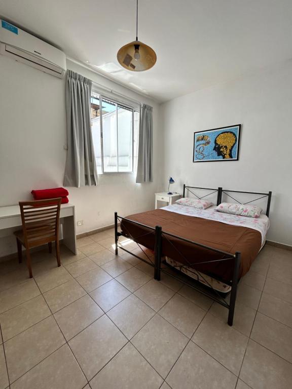 um quarto com uma cama, uma cadeira e uma janela em Reina Madre Hostel em Buenos Aires