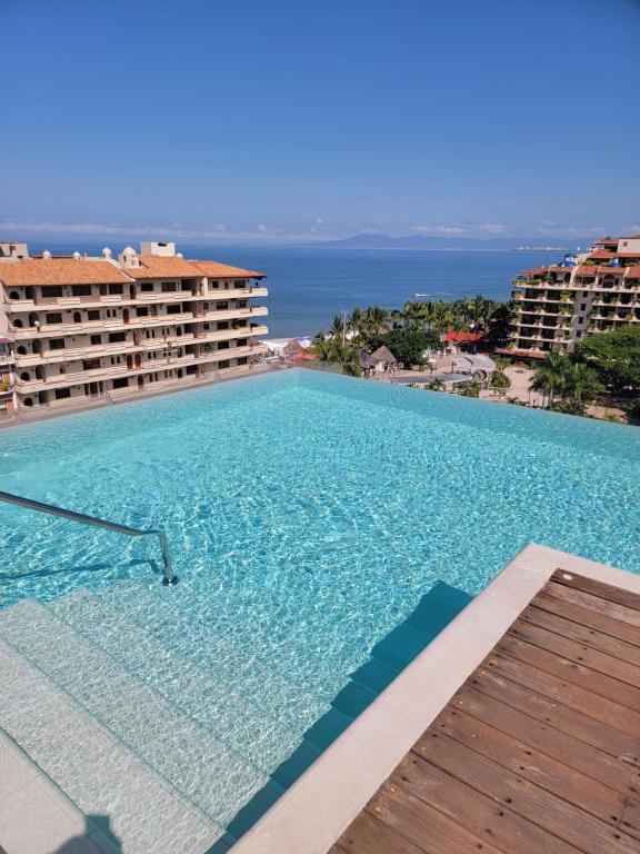 a large swimming pool with a view of the ocean at Nayri Beach and restaurant row in Puerto Vallarta