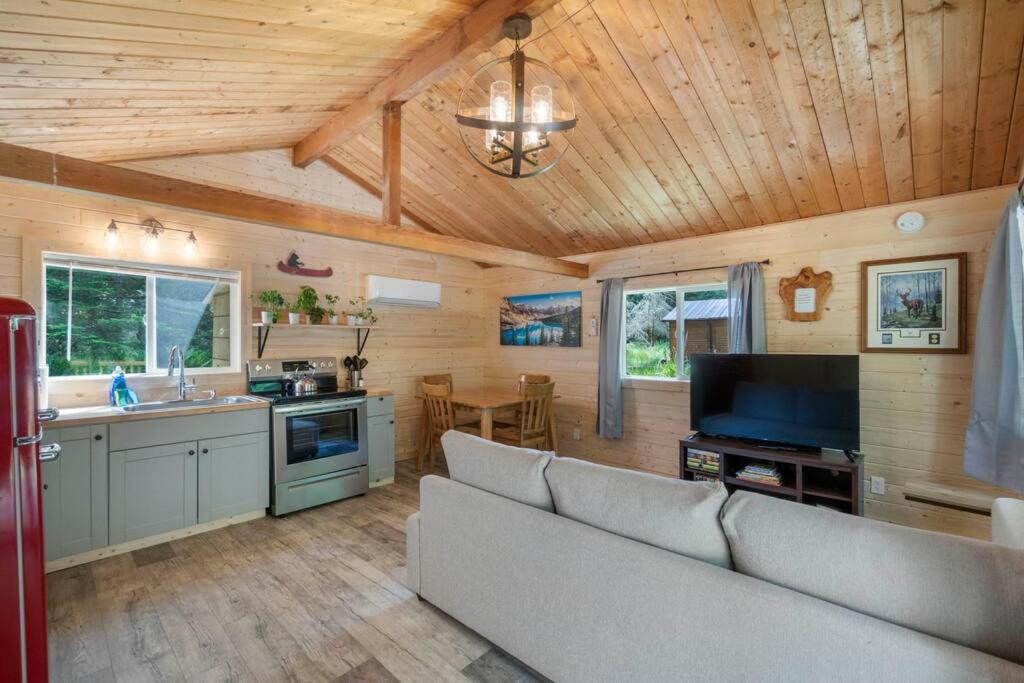 sala de estar con sofá y TV y cocina en Cozy Cedar Cabin Steps Away From Mt. Rainier en Ashford