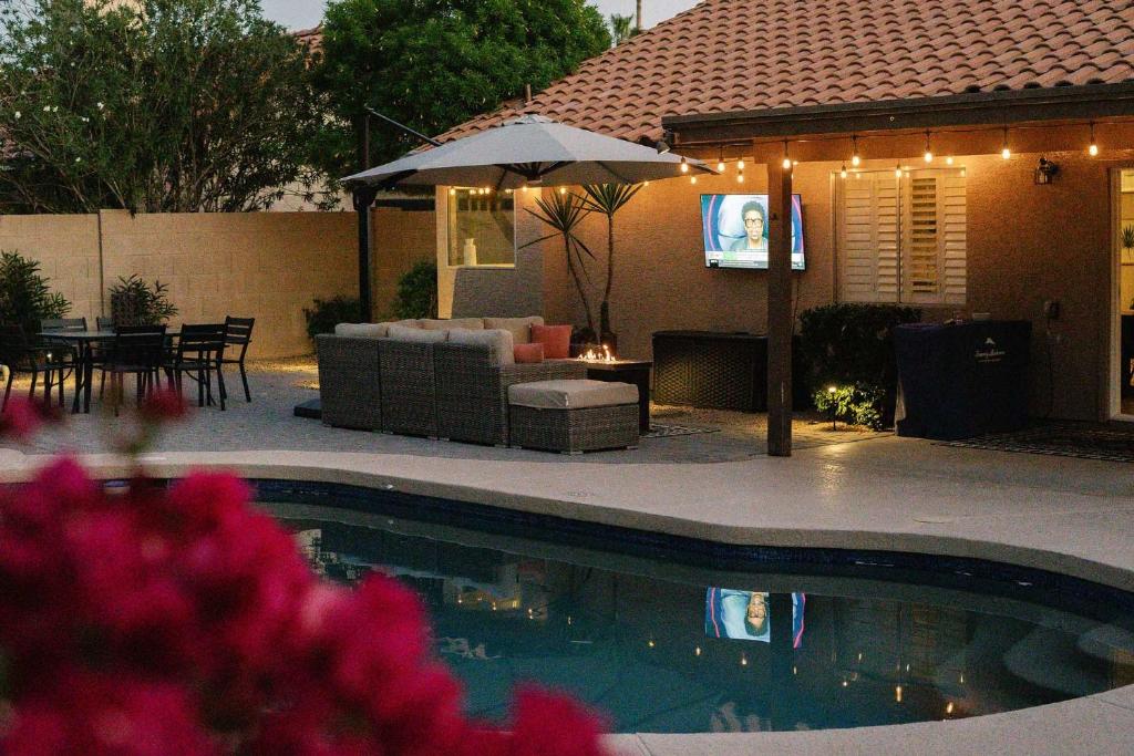 a backyard with a pool with a couch and an umbrella at Sunny Scottsdale Retreat with Private Pool and Hot Tub in Phoenix
