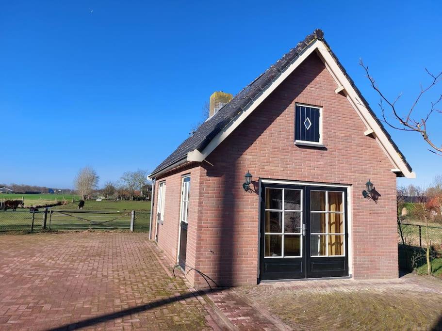 a red brick building with a window and a field at Tiny house Wakker in Eemnes