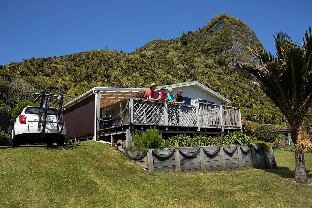 three people sitting on the balcony of a house at Driftwood Cottage in Punakaiki