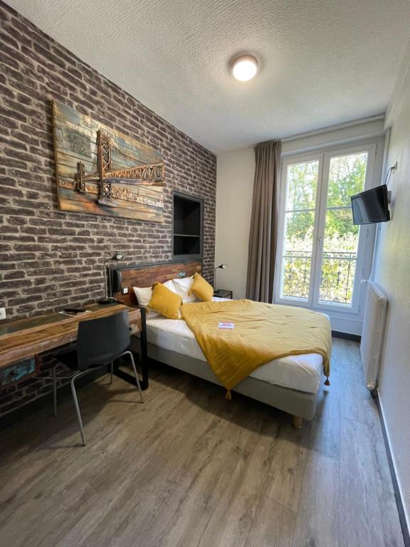 a bedroom with a bed and a brick wall at Le Richelieu Bacchus in Fontainebleau