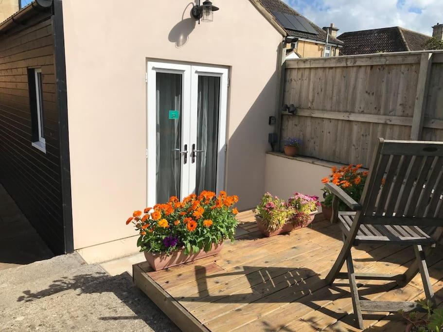 eine Terrasse mit einem Stuhl, Blumen und einem Zaun in der Unterkunft Garden studio in Bradford on Avon in Bradford on Avon