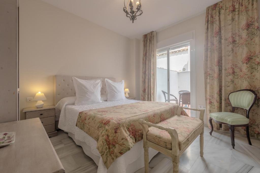 a bedroom with a bed and a chair and a window at SunShine Templo Romano in Córdoba