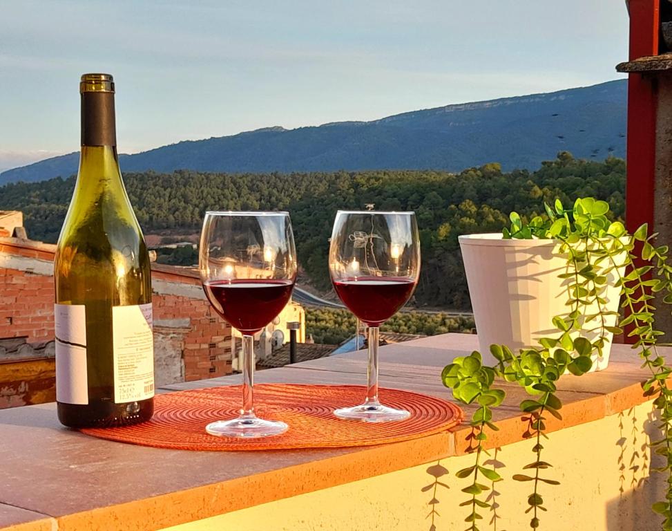 zwei Gläser Wein auf dem Tisch mit einer Flasche Wein in der Unterkunft Cal Passió in Vimbodí