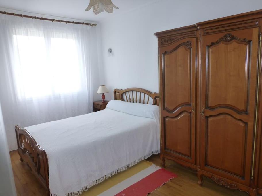ein Schlafzimmer mit einem Bett und einem großen Holzschrank in der Unterkunft Appartement 60 m2 indépendant au 1er étage d'une maison de ville in Lanester