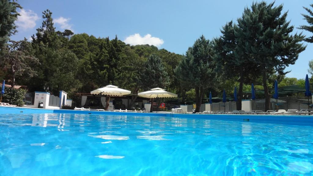 una grande piscina con acqua blu e ombrelloni di Villaggio Camping Le Ninfe del Mare a Palinuro